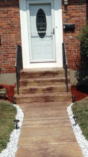 White front door with oval window on brick house with concrete steps and white gravel landscaping