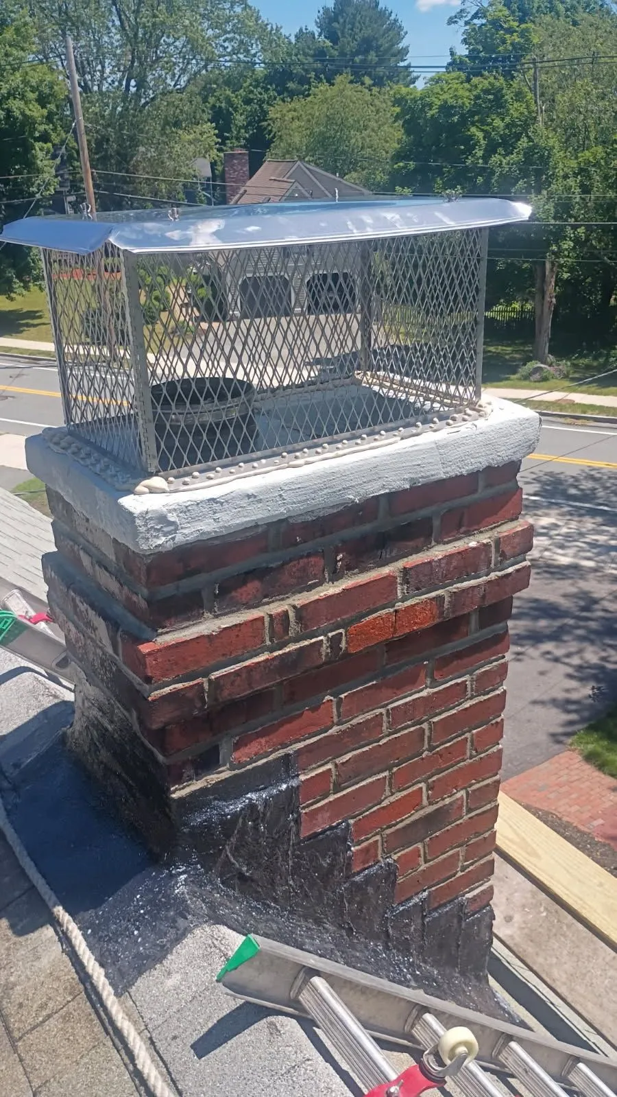 Metal chimney cap with expanded metal mesh cage mounted on brick chimney structure