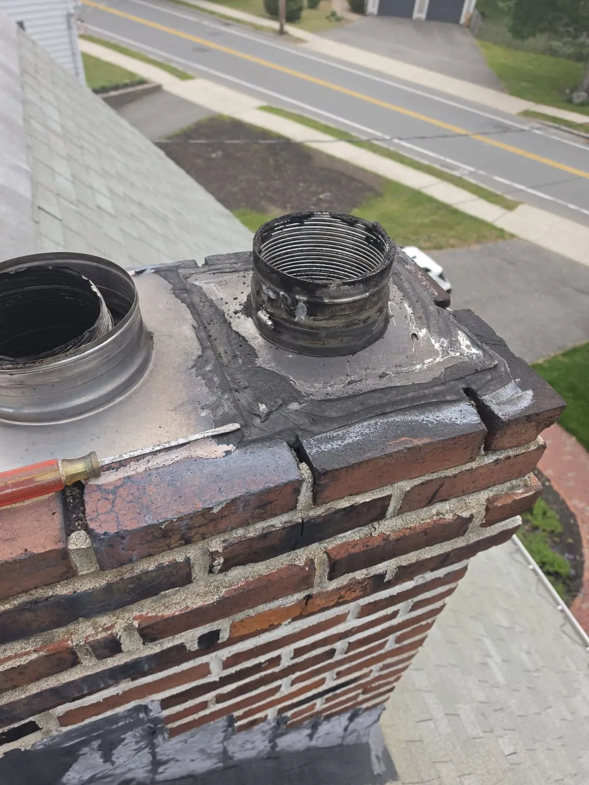 Damaged chimney flashing and vent pipe on brick chimney top