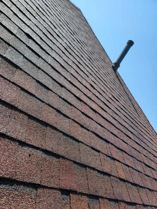 Brick building exterior with diagonal architectural lines and a black pipe fixture against blue sky